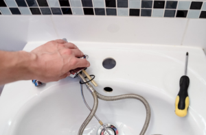 a hand fixing a bathroom tap 